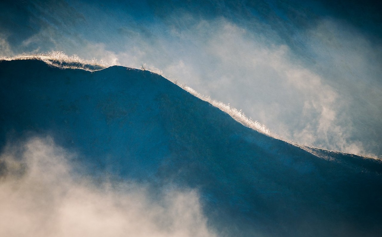 A ridge and low sun emerge through blue-grey cloud over the hills around Bologna.