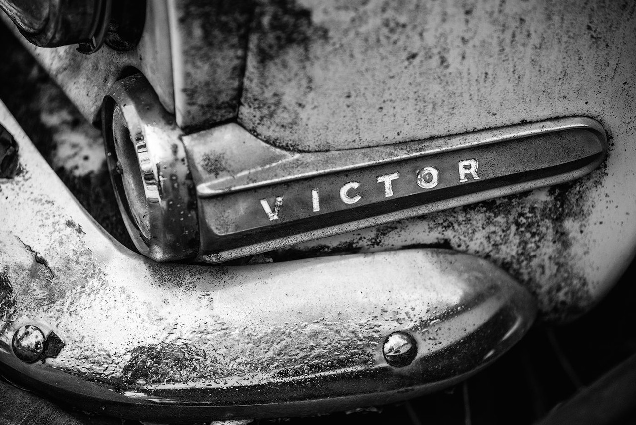 A close black-and-white view of the Victor nameplate on a weathered car.
